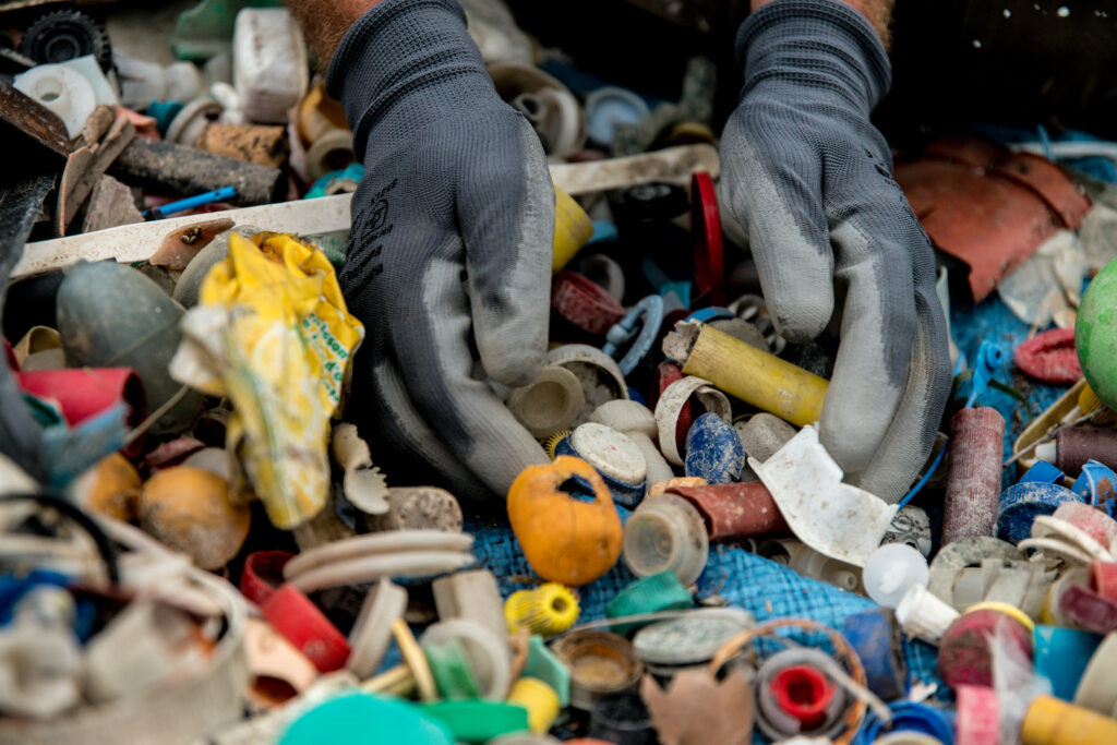 Mains gantées triant des déchets plastiques collectés lors d’une opération de dépollution menée avec Wings of the Ocean près de l’étang de Berre. © Ludivine TESSIER